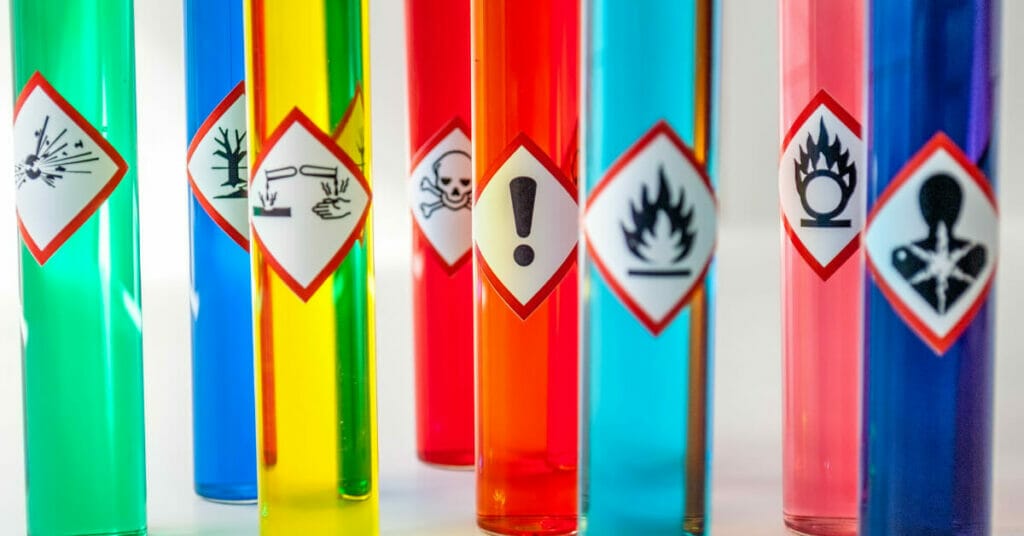 A collection of colored tubes featuring hazard symbols, highlighting health risks associated with epoxy resin.