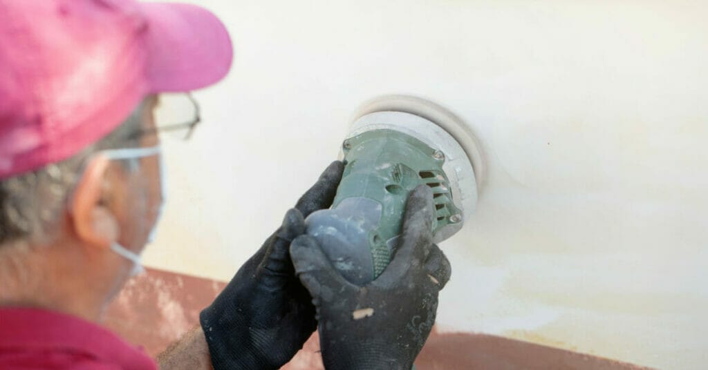 A man is sanding a wall.