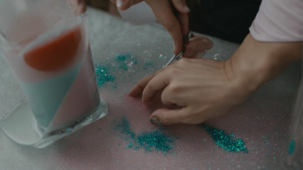 A person pouring epoxy into a glass while adding glitter for beautiful glitter tumblers.
