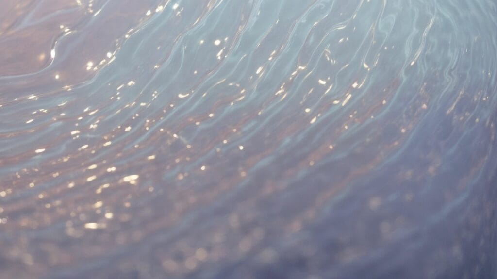 A close up of a captivating wave in the water, resembling the ethereal qualities of liquid glass.